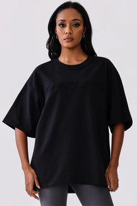 Black oversized activewear tee with embossed logo, paired with leggings for workout or casual wear