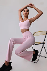 Woman in pink activewear set with sports bra and flared leggings, seated on chair for workout or yoga