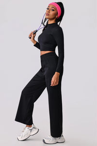 Woman in black activewear set with pink headband holding tennis racket, stylish workout outfit