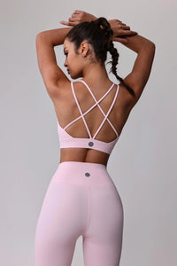 Woman in pink activewear set with crisscross back sports bra and high-waisted leggings