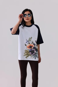 Woman in floral print raglan t-shirt with navy sleeves, styled with leggings and sunglasses for activewear look