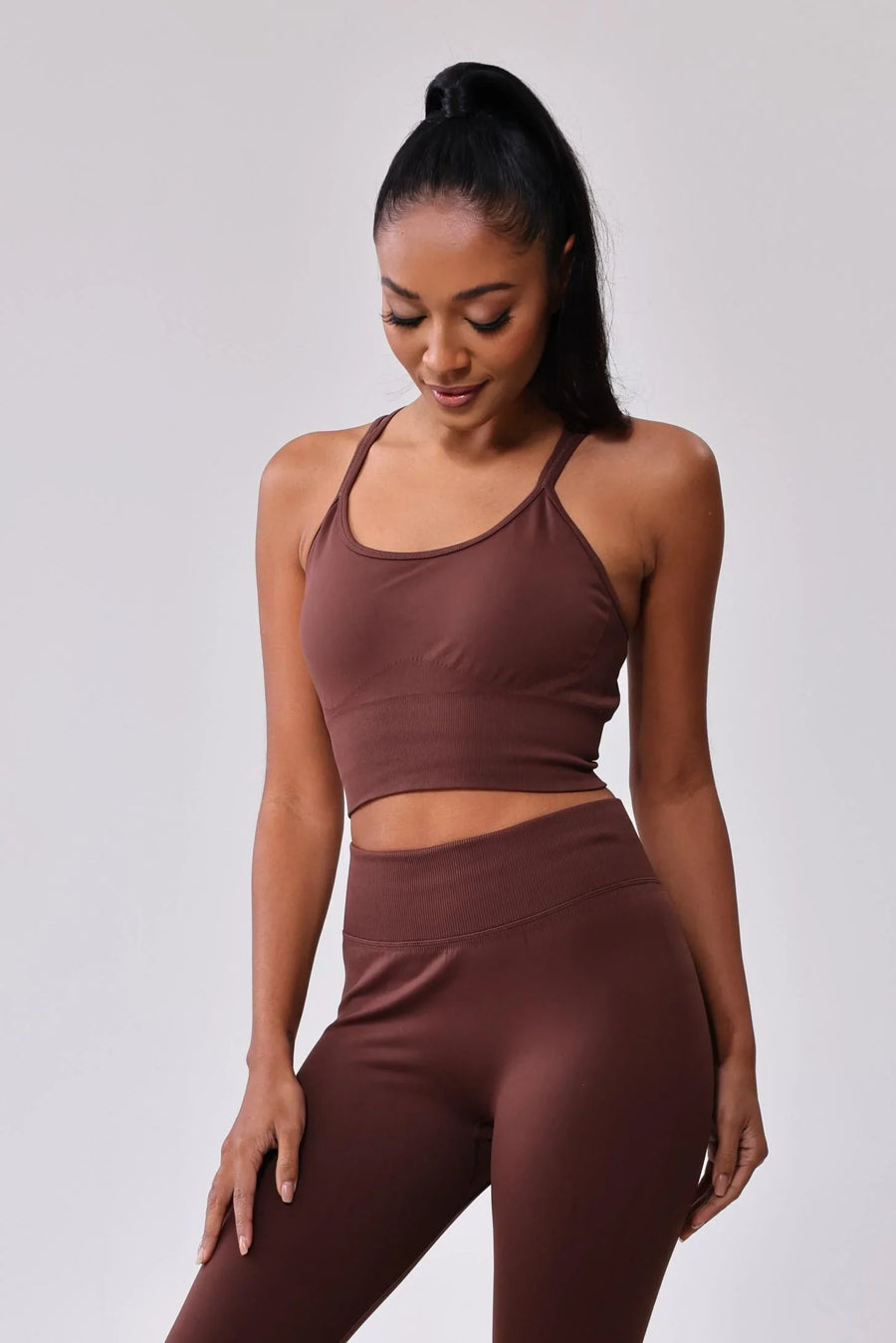 Woman in matching brown activewear set: sports bra and high-waisted leggings for gym or yoga
