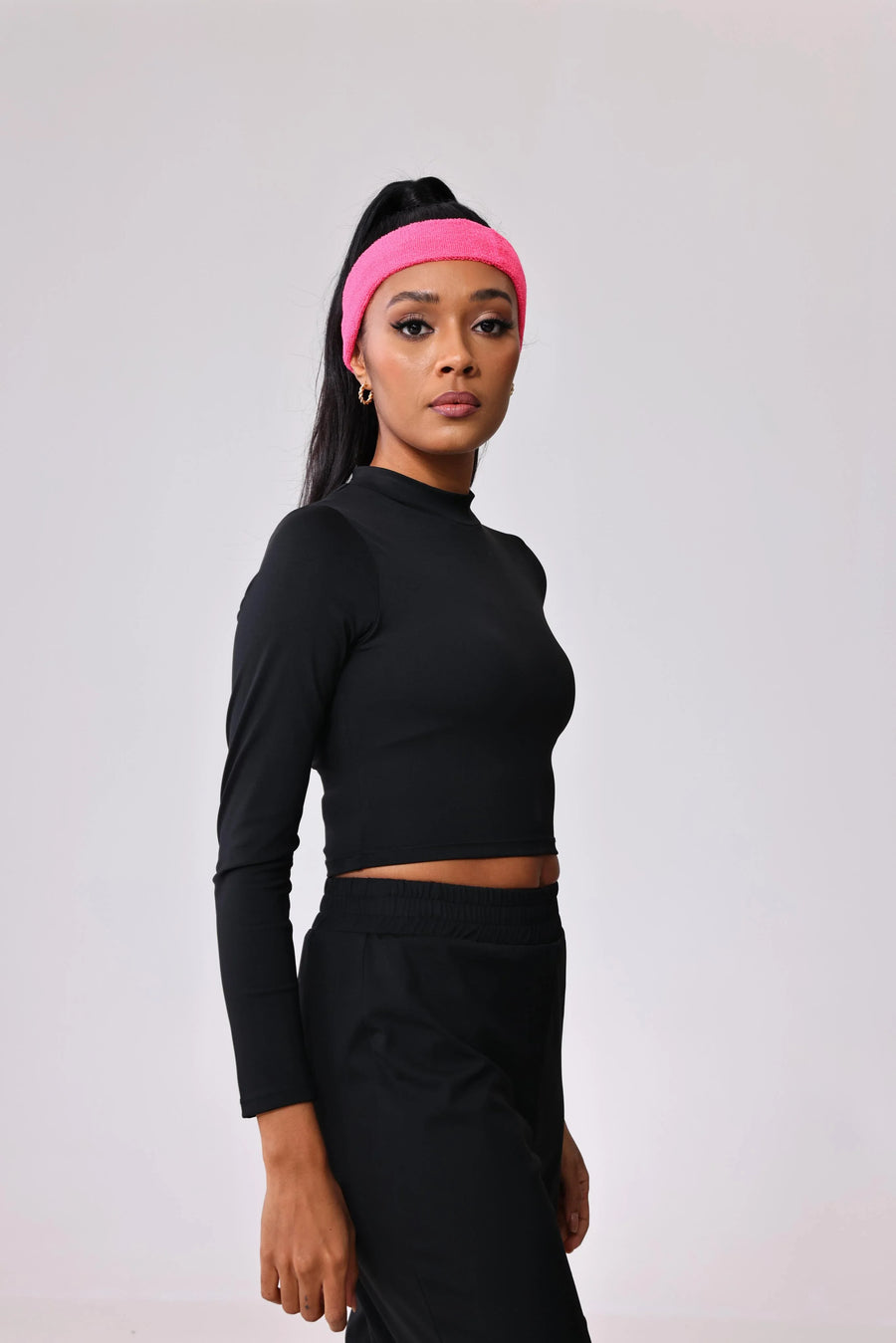 Woman in black long sleeve crop top and matching pants with pink headband, activewear for gym or everyday wear
