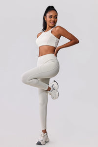 Woman in cream ribbed activewear set with high-waisted leggings and sports bra, styled with white sneakers for workout or casual wear.