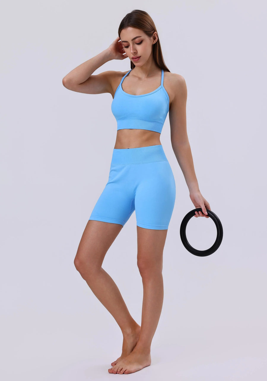 Woman in light blue activewear set with sports bra and biker shorts, holding fitness ring