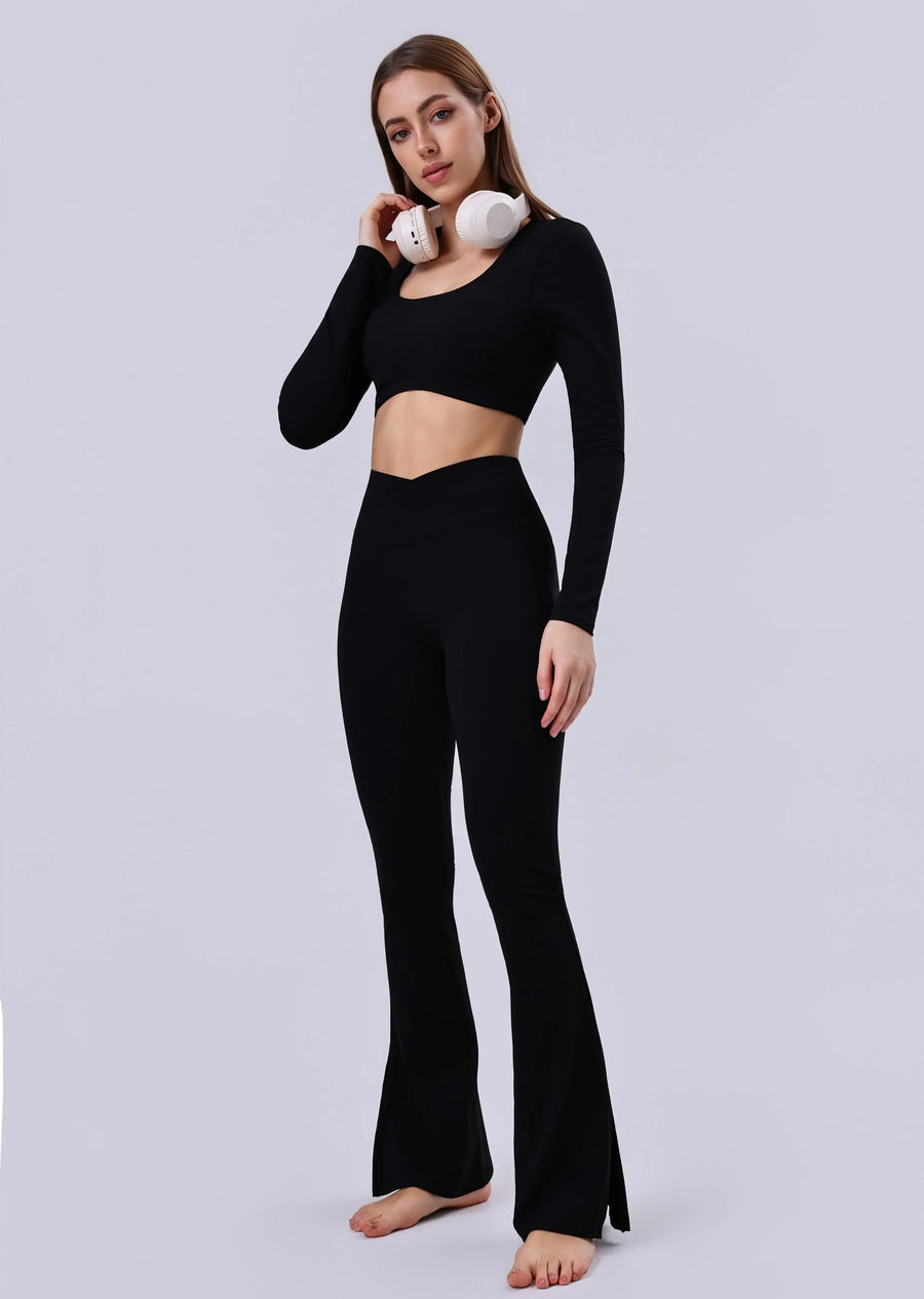 Woman in black long sleeve crop top and flared leggings with white headphones, activewear set