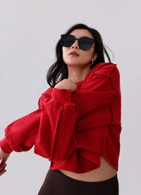 Woman in red cropped hoodie with ruffled sleeves, black leggings, and sunglasses for activewear