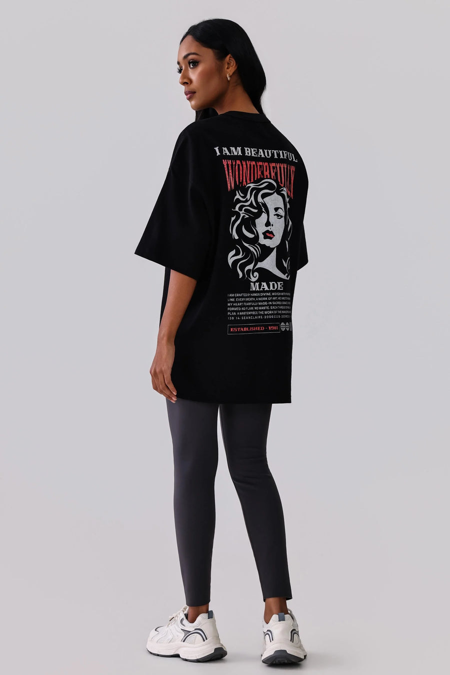 Woman in black graphic tee with 'I Am Beautiful Wonderfully Made' text, paired with leggings and white sneakers