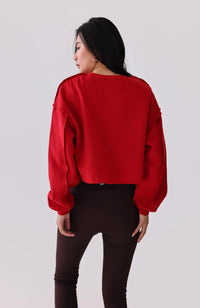 Woman in red cropped sweatshirt with puff sleeves and black leggings, activewear outfit