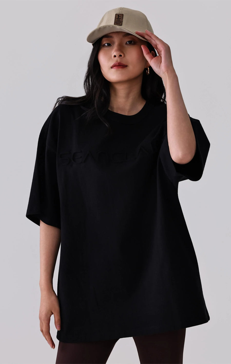 Woman in black oversized t-shirt and beige cap, casual activewear style