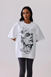 White oversized graphic tee with black floral and face line art, paired with black leggings for activewear