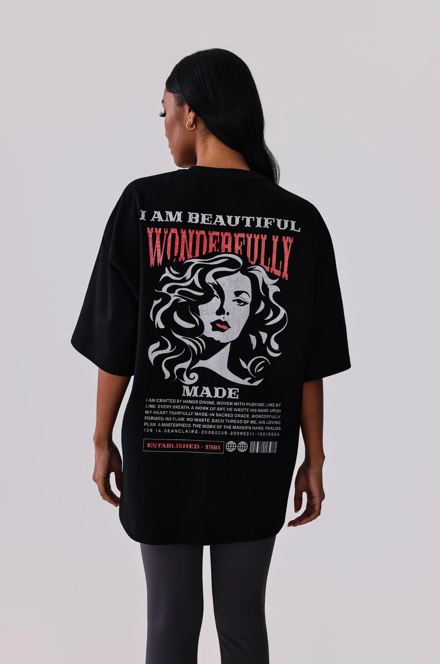 Black oversized graphic tee with 'I Am Beautiful Wonderfully Made' print, worn with leggings for activewear style.