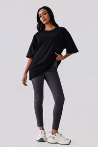 Woman in black oversized activewear tee and gray leggings with white sneakers, stylish gym outfit
