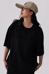 Woman in black oversized t-shirt and beige baseball cap, stylish activewear look