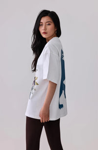 Woman in white graphic tee with floral and blue print, paired with black leggings for activewear