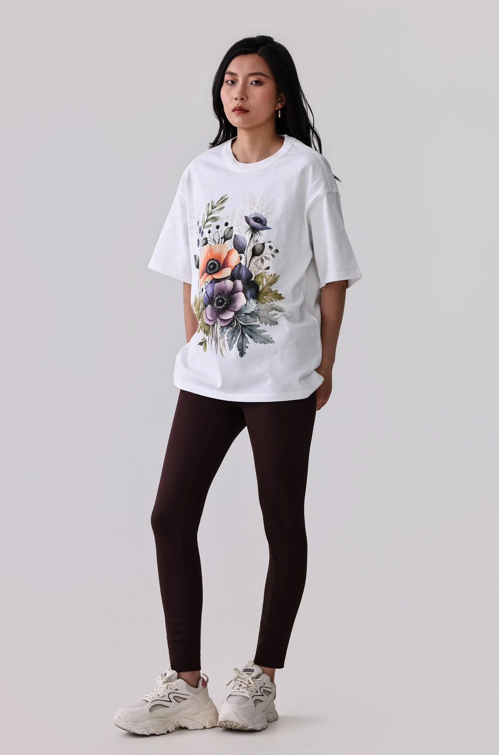 White floral print activewear tee with dark leggings and white sneakers for women's fitness style