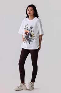 White floral print activewear tee with dark leggings and white sneakers for women's fitness style