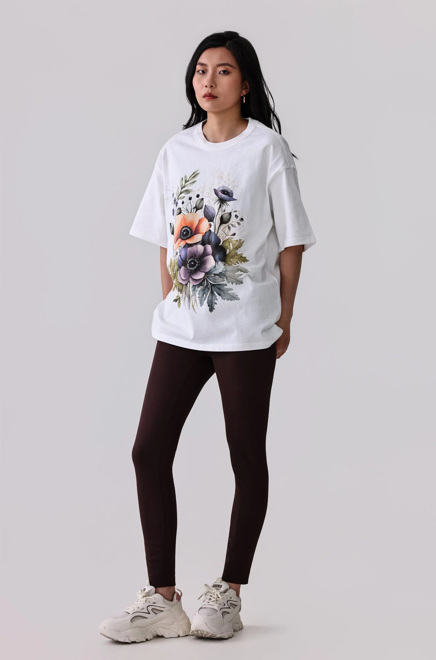 White floral print activewear tee with dark leggings and white sneakers for women's fitness style