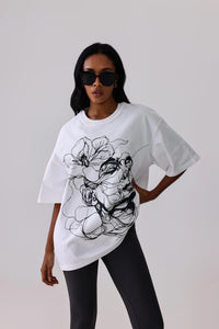 White oversized graphic tee with black line art, paired with black leggings for activewear
