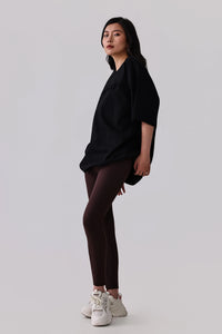 Woman in black oversized activewear tee and dark leggings with white sneakers, studio shot